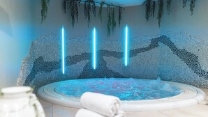 A spa area with a hot tub, towels, and a decorative wall with hanging plants. - Apartmenthaus Hotel Cella Central (Zell am See)