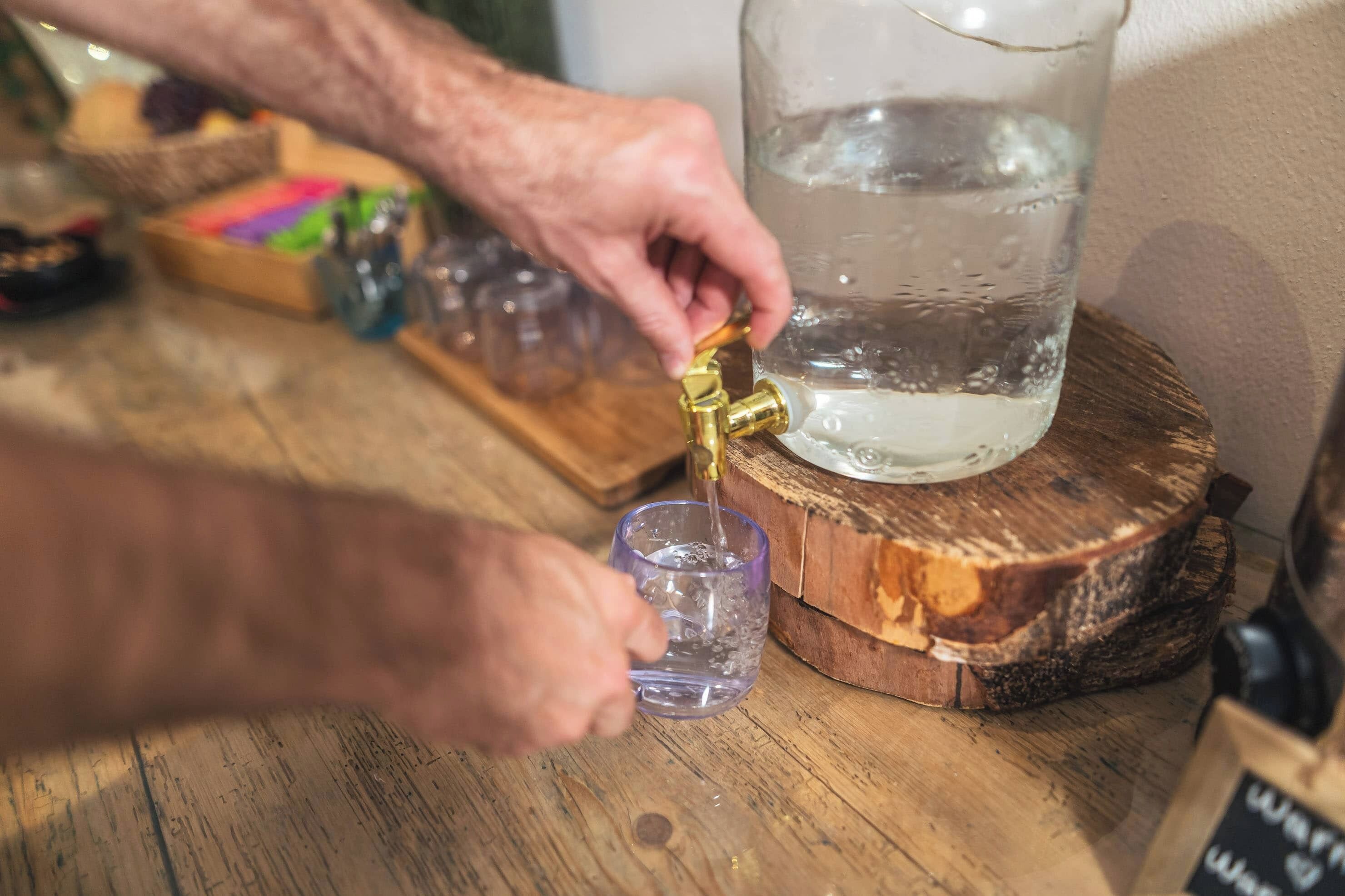 A person filling a glass with water from a tap.