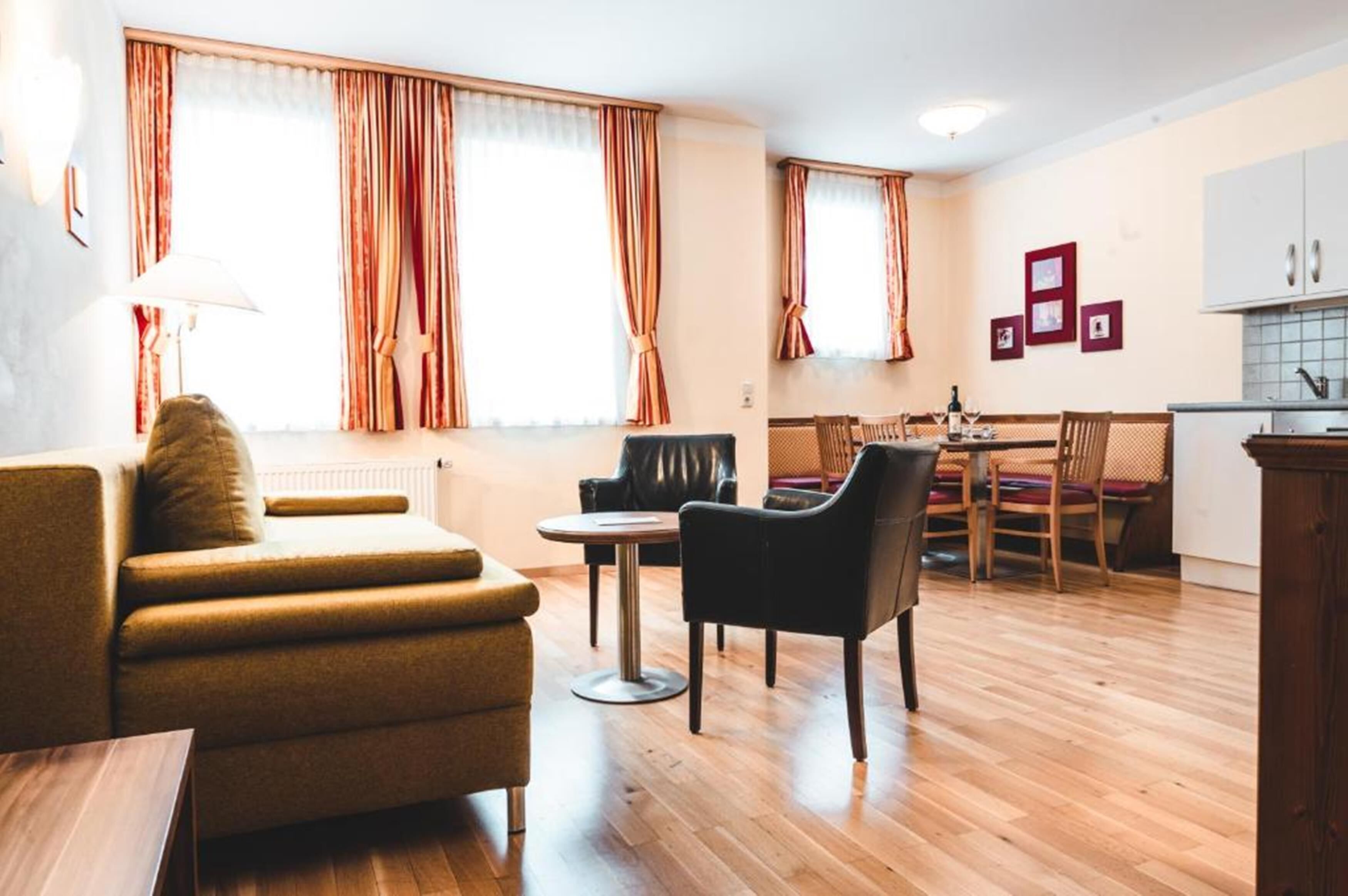 Un salon moderne comprenant un canapé, des fauteuils, une table à manger et un coin cuisine.
