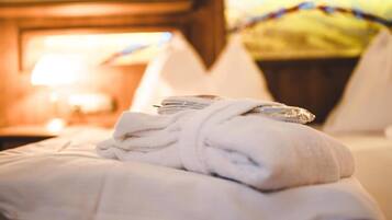 A neatly made bed with a folded white towel and a rolled-up towel on top.