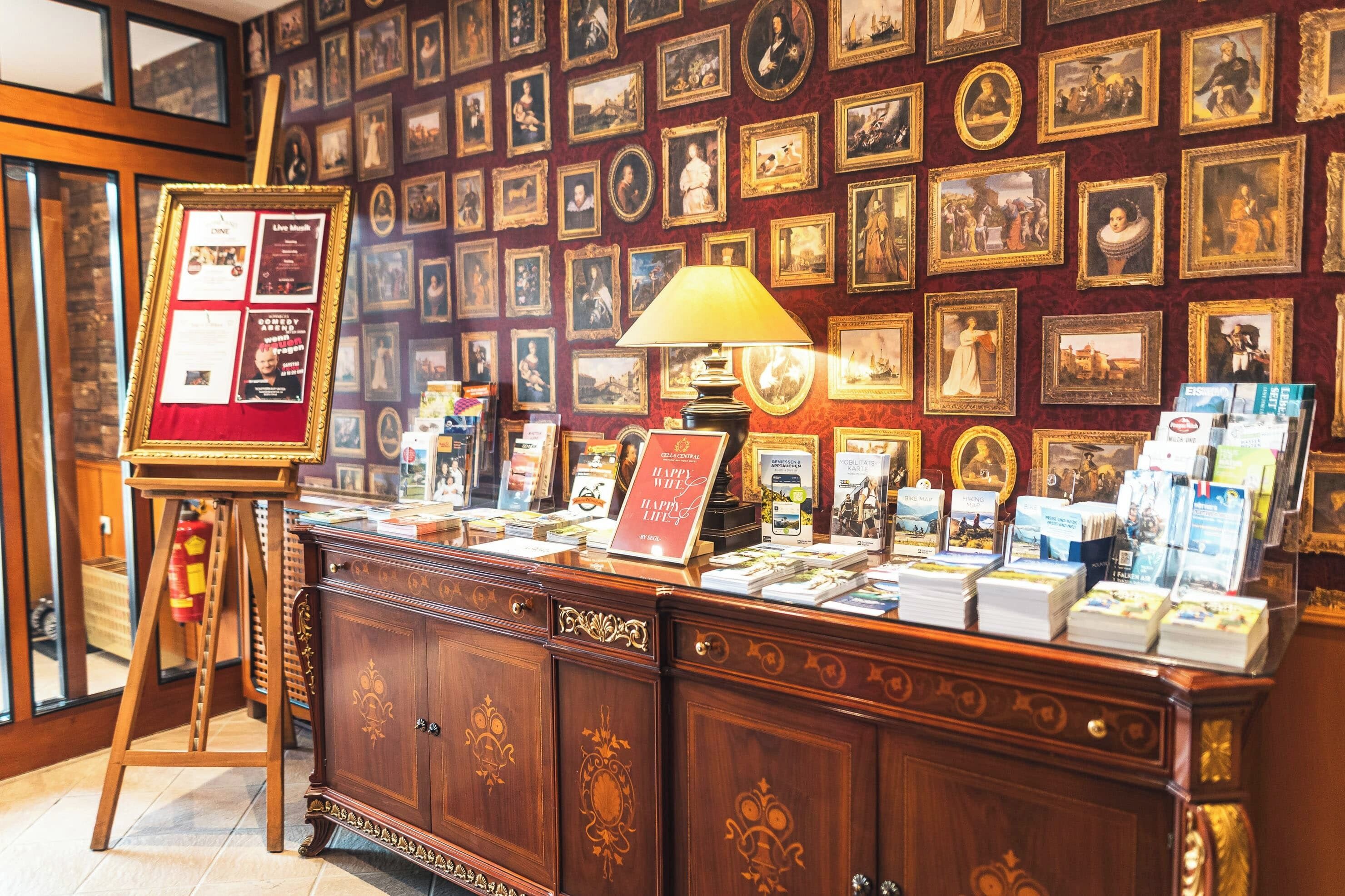 A room with a wooden cabinet displaying books and a framed poster on a stand.