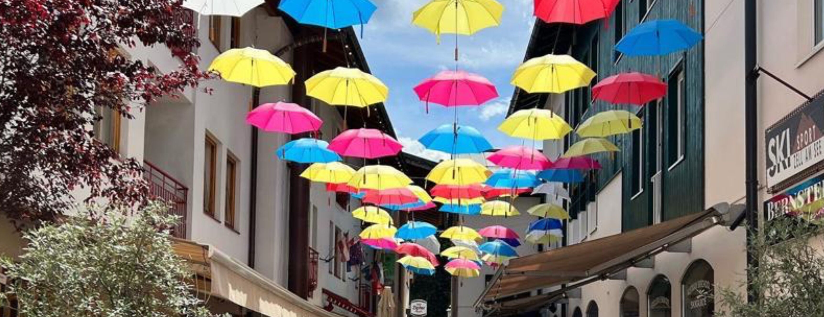 Una calle con paraguas de colores colgando.