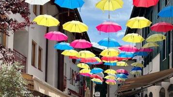 Una calle con paraguas de colores colgando.