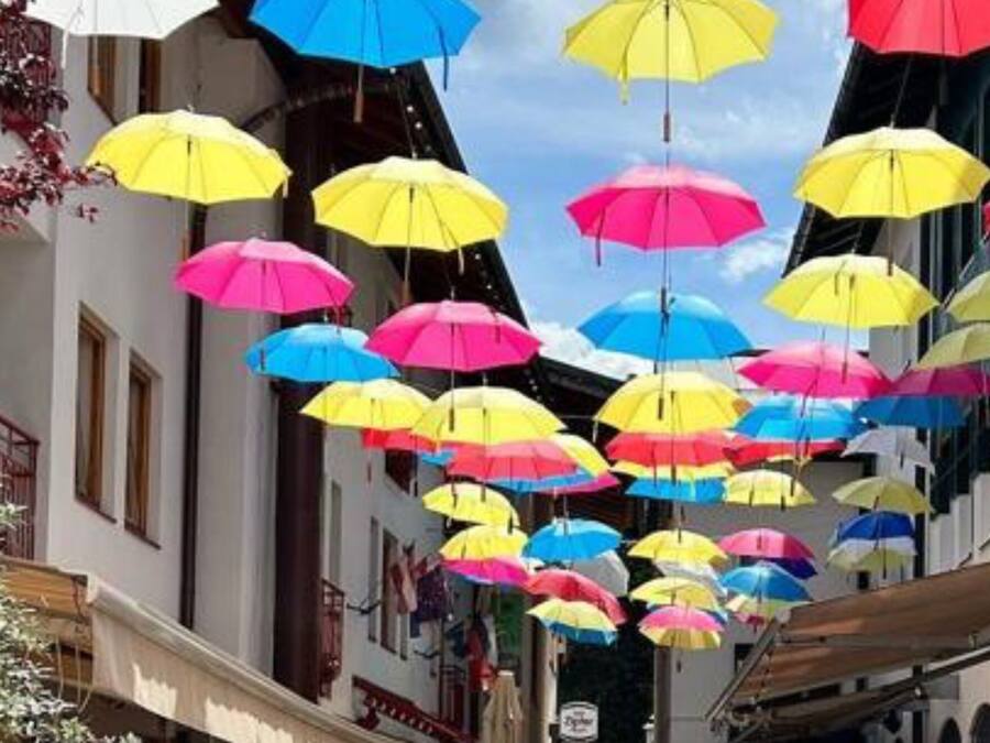 Una calle con paraguas de colores colgando.