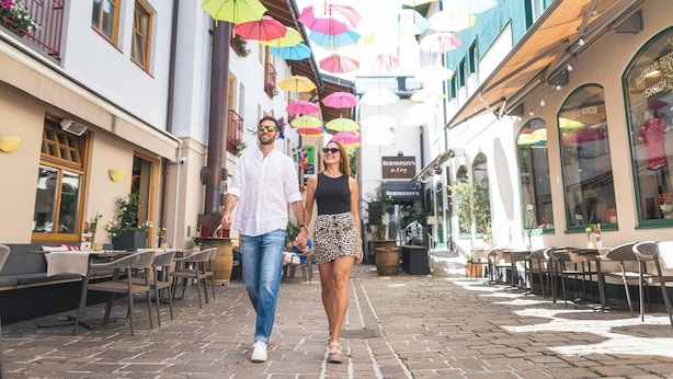 A cobblestone street with outdoor seating and umbrellas. - Apartmenthaus Hotel Cella Central (Zell am See)