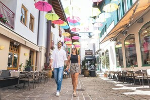 Una calle empedrada con mesas al aire libre y sombrillas.