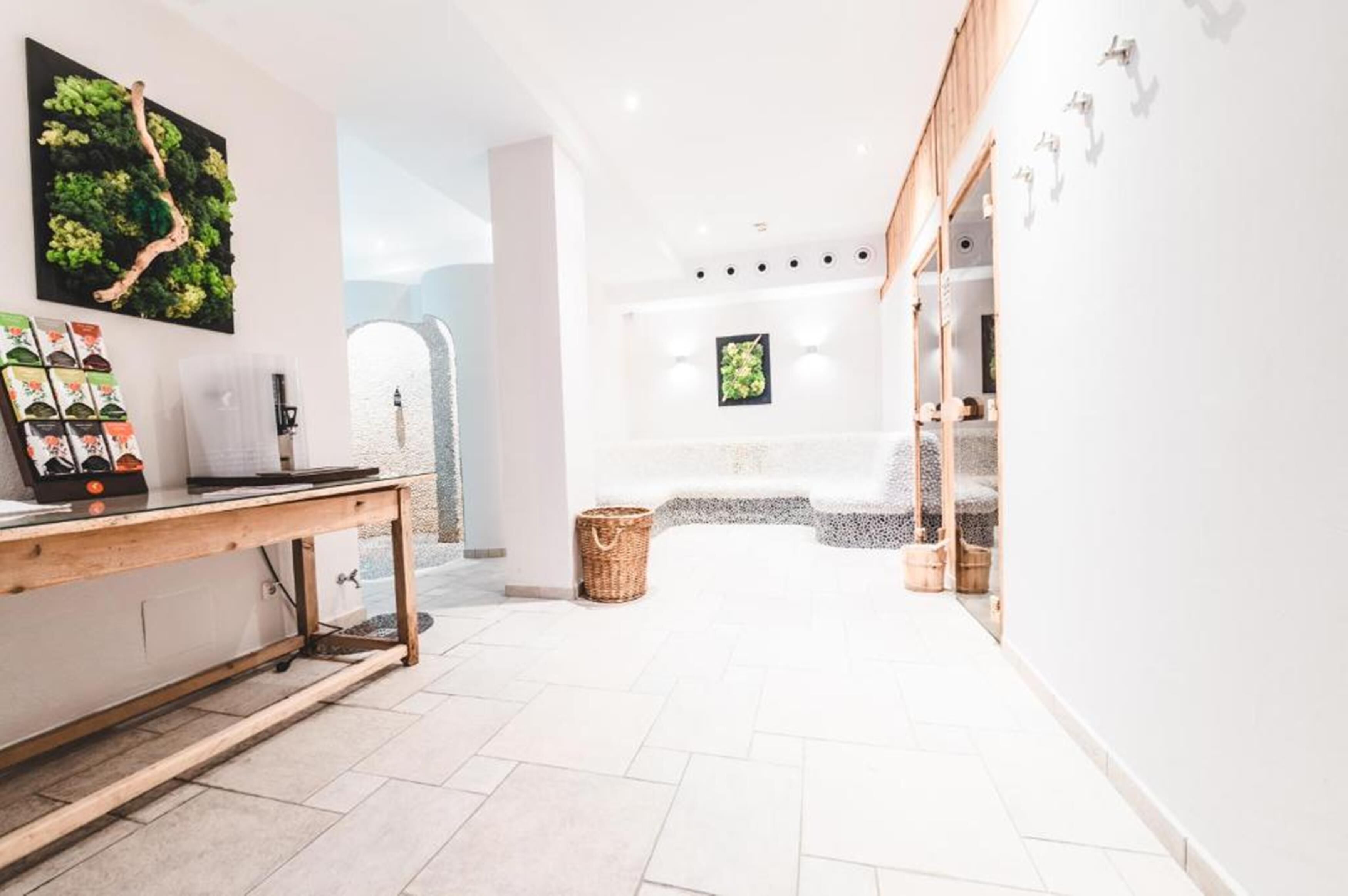 Een helder, modern interieur met een houten tafel, een wandplant en een stenen bank.