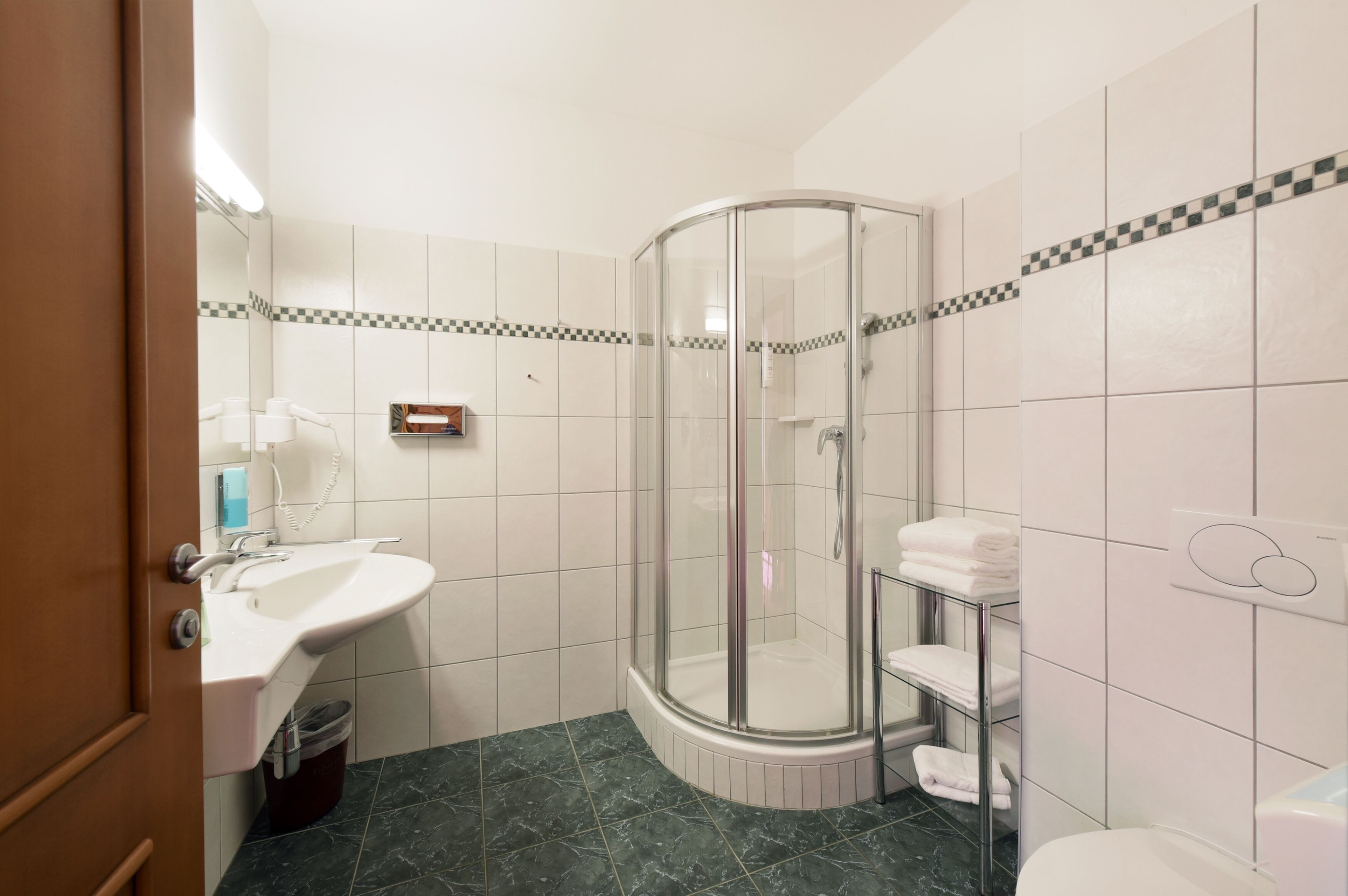 Uma casa de banho com cabine de duche de vidro, lavatório com espelho e sanita.