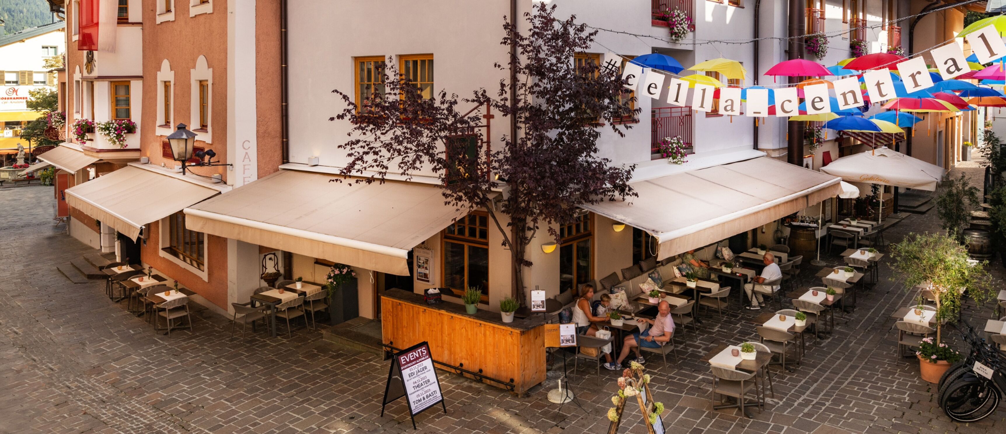 Un café en plein air avec des tables et des chaises, un comptoir en bois et une enseigne.