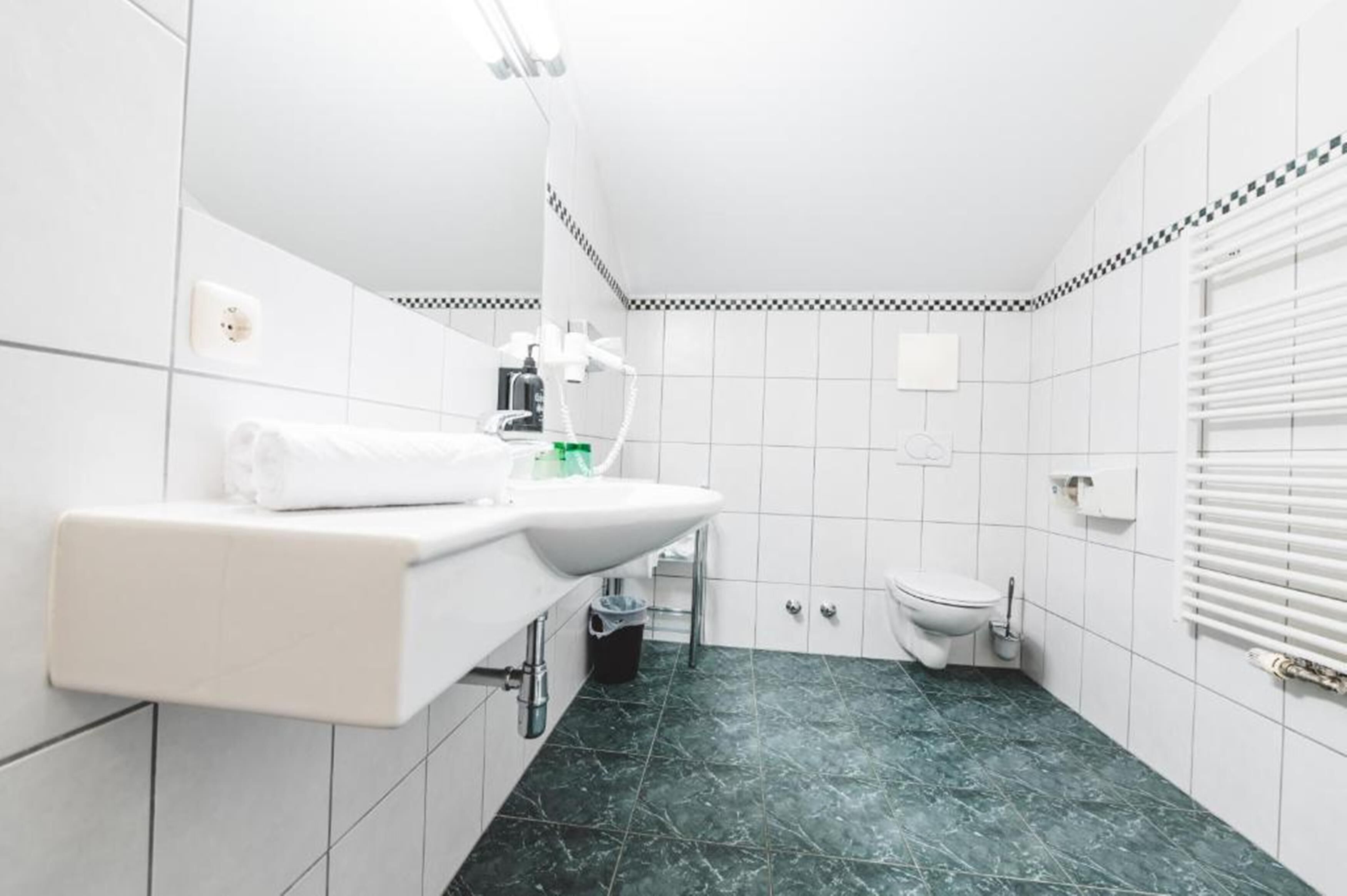 Ett modernt badrum med ett vitt handfat, en toalett och en dusch.