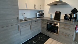 A modern kitchen with grey cabinetry, a stainless steel oven, a microwave, and a coffee maker. - High Franconia apartment  (Oberkotzau)