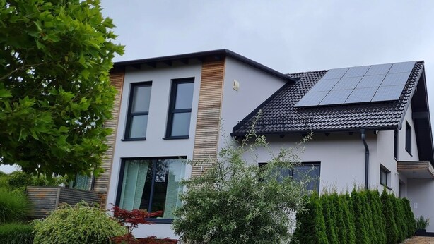 A modern two-story house with a solar panel roof, a paved driveway, and a well-maintained garden. - High Franconia apartment  (Oberkotzau)