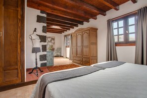 A bedroom with a bed, wooden wardrobe, and a mannequin.