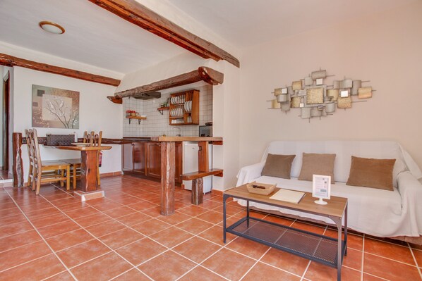 A living room with a sofa, a coffee table, and a dining area with chairs and a table.