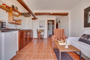Une cuisine avec des meubles en bois, un réfrigérateur et un coin repas comprenant une table et des chaises.