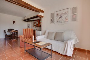 A living room with a sofa, a coffee table, a striped armchair, a dining table with chairs, and a kitchen in the background. - Charming Apartment "2" with Terrace, Community Pool & Wi-Fi (La Asomada)