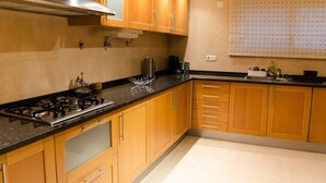 A kitchen with wooden cabinets, a gas stove, and a window with blinds. - JOIVY Graca Luminous 2-BR Apartment w/Terrace (Lisboa)