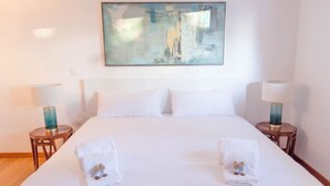 A hotel room with a large bed, two bedside tables with lamps, a painting on the wall, and towels on the bed. - JOIVY Graca Luminous 2-BR Apartment w/Terrace (Lisboa)