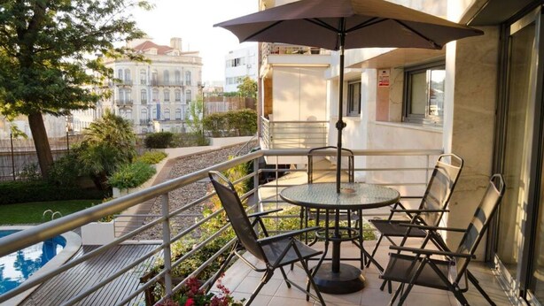 A balcony with a pool, outdoor seating, and a view of buildings. - JOIVY Graca Luminous 2-BR Apartment w/Terrace (Lisboa)