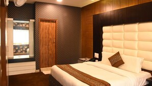 Una habitación de hotel con una cama, un armario de madera, una mesita de noche y una ventana con vistas.
