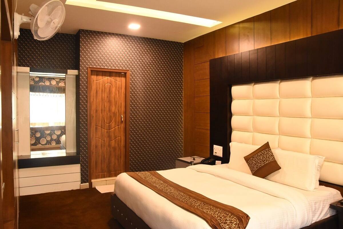 Ein Hotelzimmer mit Bett, Holzschrank, Nachttisch und Fenster mit Blick.