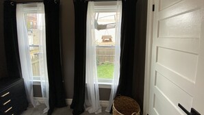 A room with two windows, a white door, and a wicker basket on the floor. - Entire Apartment walking distance to Cincy River front and COV Wedding Venues (Covington)