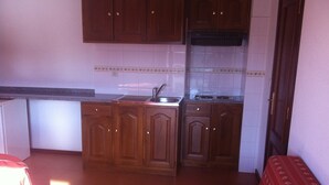 A compact kitchen with wooden cabinets, a sink, and a stove. - Guest House Casa dos Serpas (Nelas)