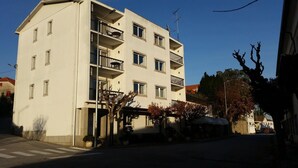 A multi-story building with balconies, a crosswalk, and trees with autumn foliage. - Guest House Casa dos Serpas (Nelas)