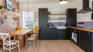 A modern kitchen with dark cabinets, a wooden countertop, and a hanging pendant light. - Macs Townhouse (Dungarvan)