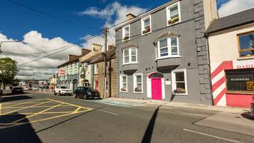 A street view with buildings, a red door, and a sign for a barber shop.