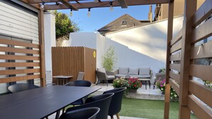 An outdoor patio with a long table and chairs, a wooden fence, and a small garden area with flowers. - Macs Townhouse (Dungarvan)