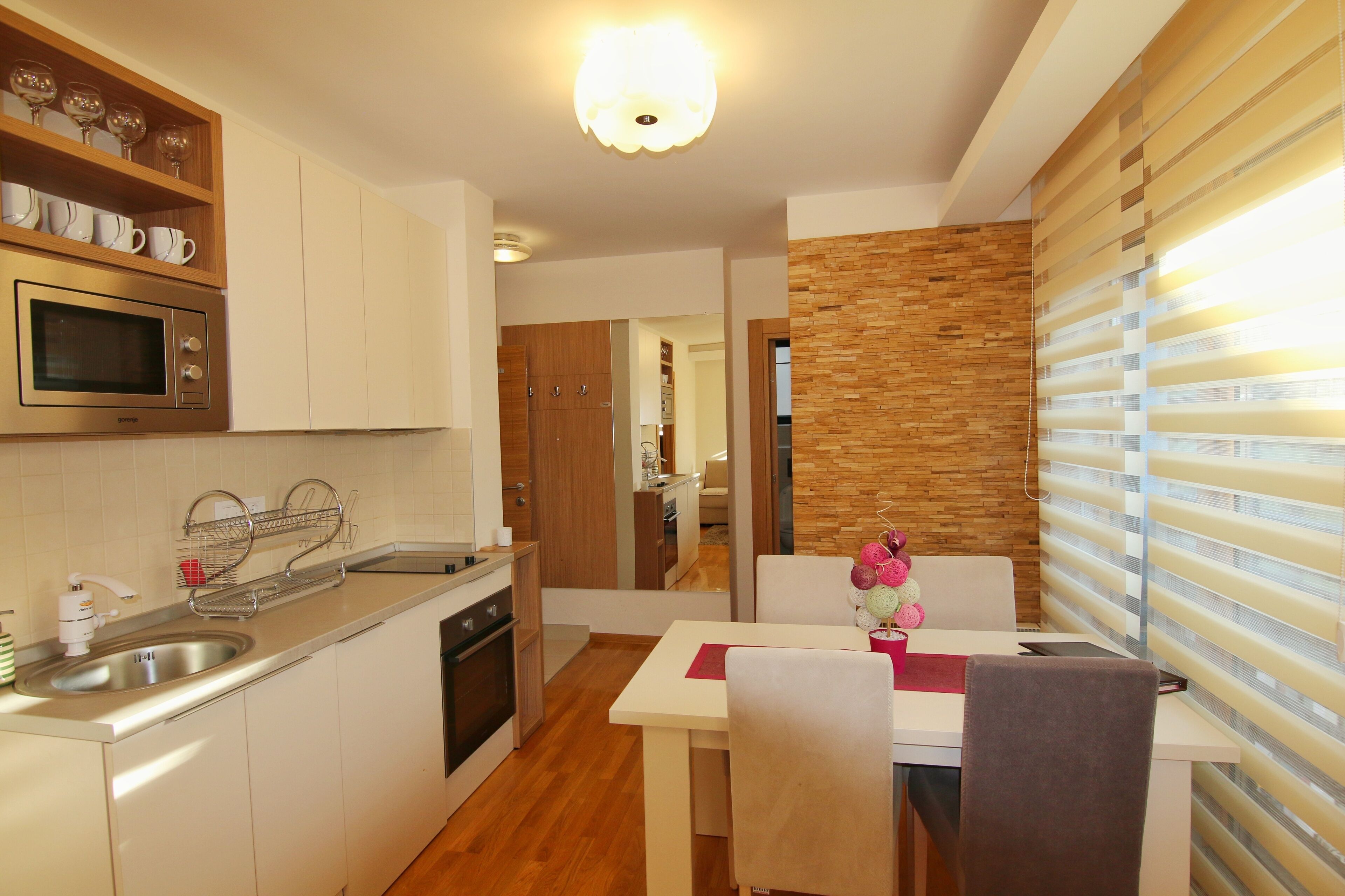 Una cocina moderna con microondas integrado, un fregadero y una zona de comedor con mesa y sillas.