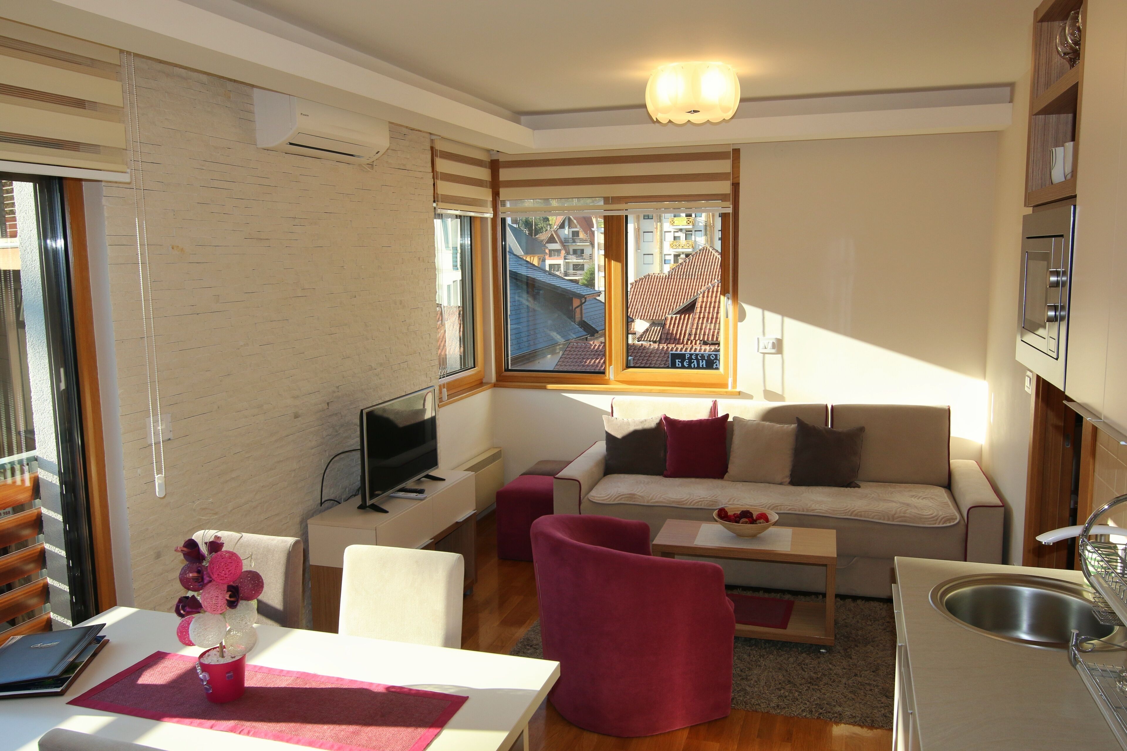 Una sala de estar moderna con sofá, sillas, televisor y un comedor con mesa y sillas.
