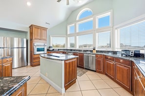 A spacious kitchen with a central island, stainless steel appliances, and large windows. - Corolla Odyssey: Dog-Friendly, Elevator, Hot Tub, Private Pool (Corolla)