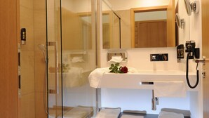 A modern bathroom with a glass-enclosed shower, a white sink with a mirror above, and a towel rack with folded towels. - Landgasthof Karolinenhöhe (Lichtenfels)