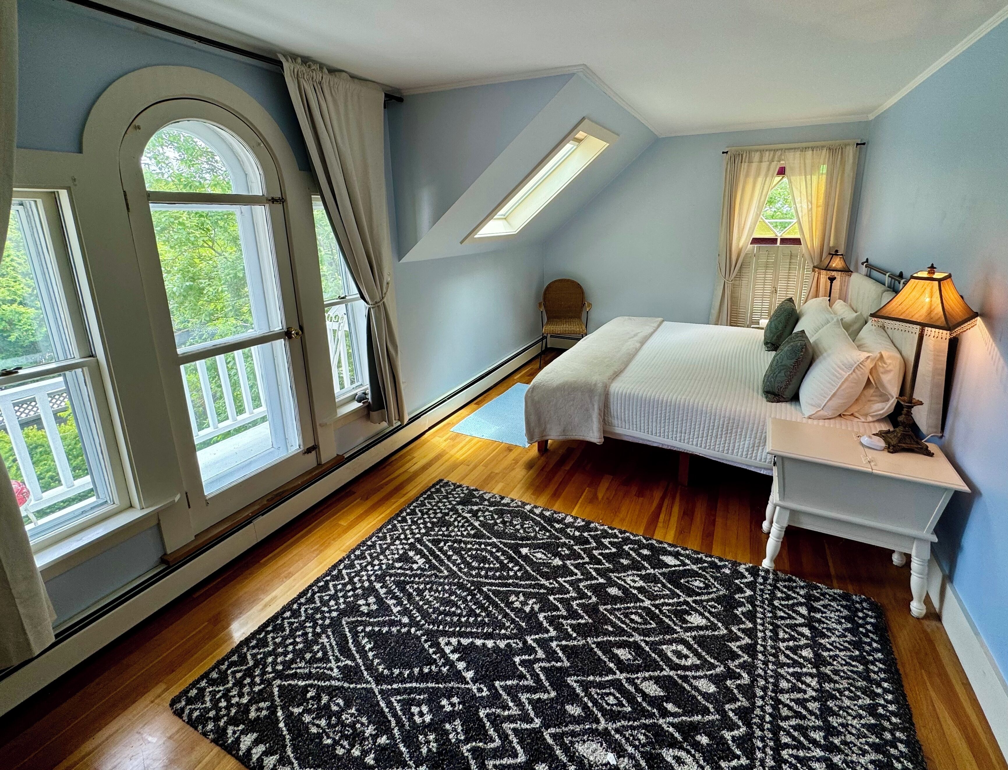 Une chambre à coucher avec un lit, une table de chevet, une lampe et un tapis à motifs.