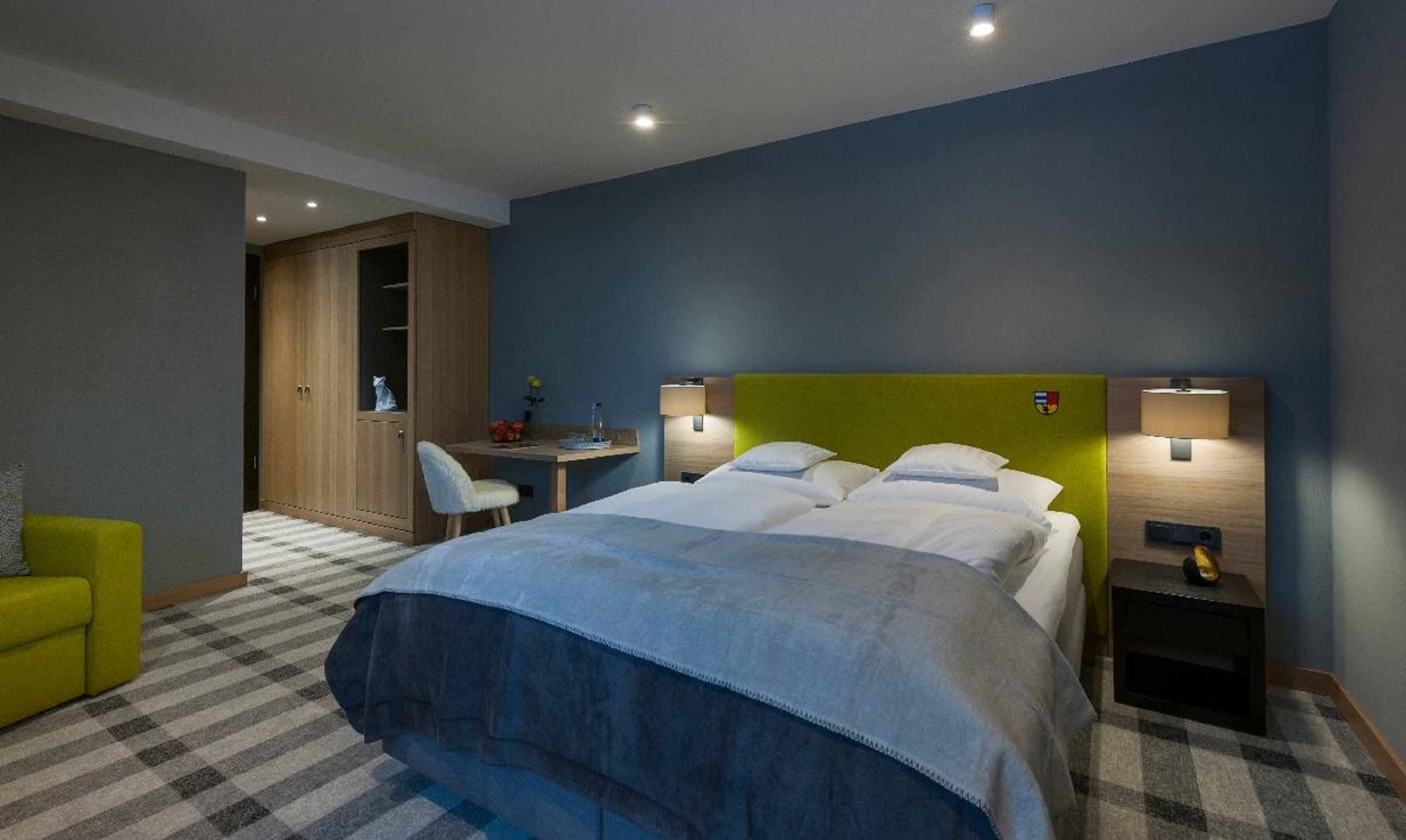 Ein Hotelzimmer mit Bett, zwei Nachttischen, einem Schreibtisch, einem Stuhl und einem Kleiderschrank.