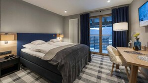 A hotel room with a bed, a desk, a chair, a TV, and a balcony with curtains. - Hotel Gasthof Fuchs (Mauth)