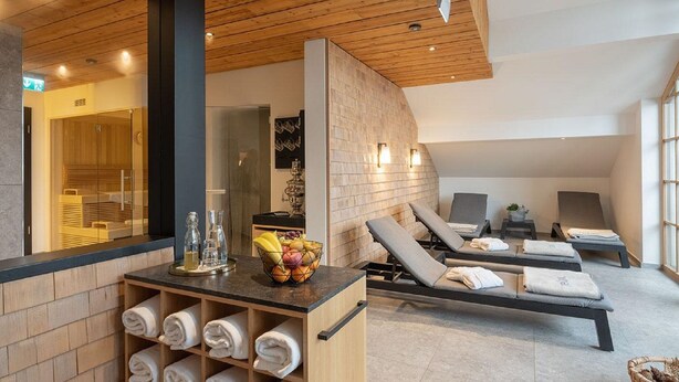 A spa area with wooden paneling, a reception desk with towels, and sun loungers. - Hotel Gasthof Fuchs (Mauth)
