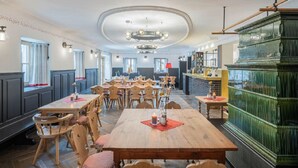 A restaurant with wooden tables and chairs, a green bar area, and a view through large windows. - Hotel Gasthof Fuchs (Mauth)