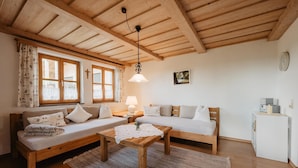 A cozy room with wooden ceilings, a sofa, a bed, a table, and a small cabinet. - Bio Ferienhof Winkler (Hutthurm)