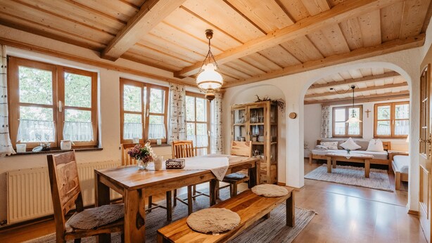A wooden interior with a dining table, benches, and a cozy seating area. - Bio Ferienhof Winkler (Hutthurm)