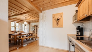 A wooden interior with a dining area, kitchen, and a wall-mounted artwork. - Bio Ferienhof Winkler (Hutthurm)
