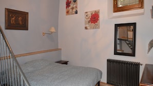 A bedroom with a bed, a radiator, a window, and wall-mounted artwork. - Appartamento in Centro (Spoleto)