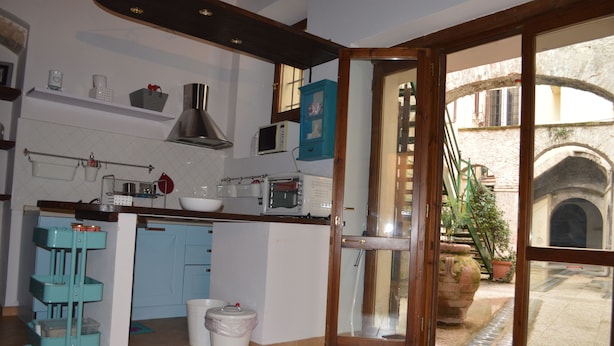 A kitchen with a microwave, toaster, and cabinets. There is a window with a view of an outdoor area. - Appartamento in Centro (Spoleto)