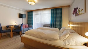 Een hotelkamer met een bed, een bureau met stoel, een televisie en een raam met gordijnen.