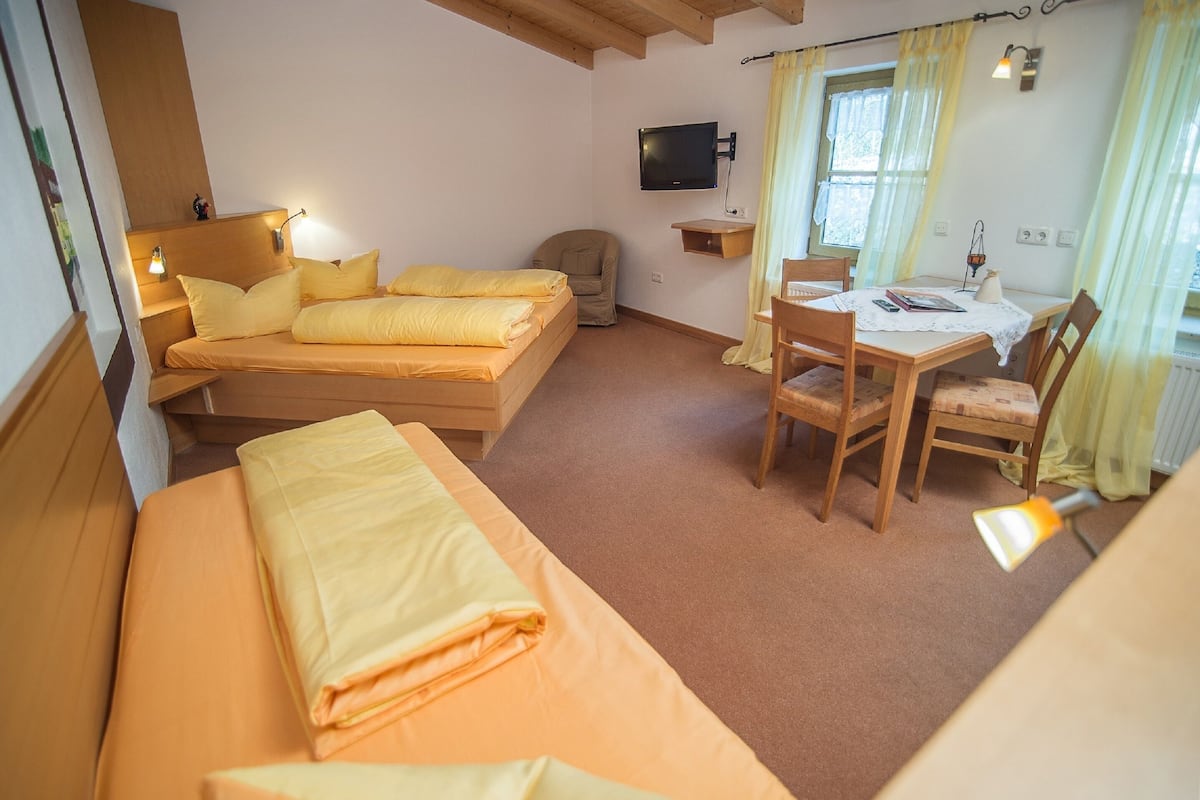 A room with a bed, a desk, a chair, a television, and a window with curtains.