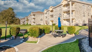 A multi-story building with stone facade, balconies, and a well-maintained lawn. - 4695 Wild Iris Drive, #204 Magnolia Place 2 Bedroom Condo by RedAwning (Myrtle Beach)