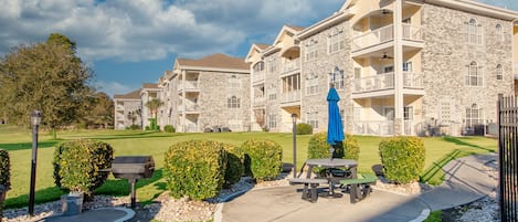 A multi-story building with stone facade, balconies, and a well-maintained lawn.
