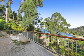 A wooden deck with outdoor furniture, a glass railing, and a view of a coastal landscape. - Wye9 Beautiful Treetop And Beach Views Open (Wye River)
